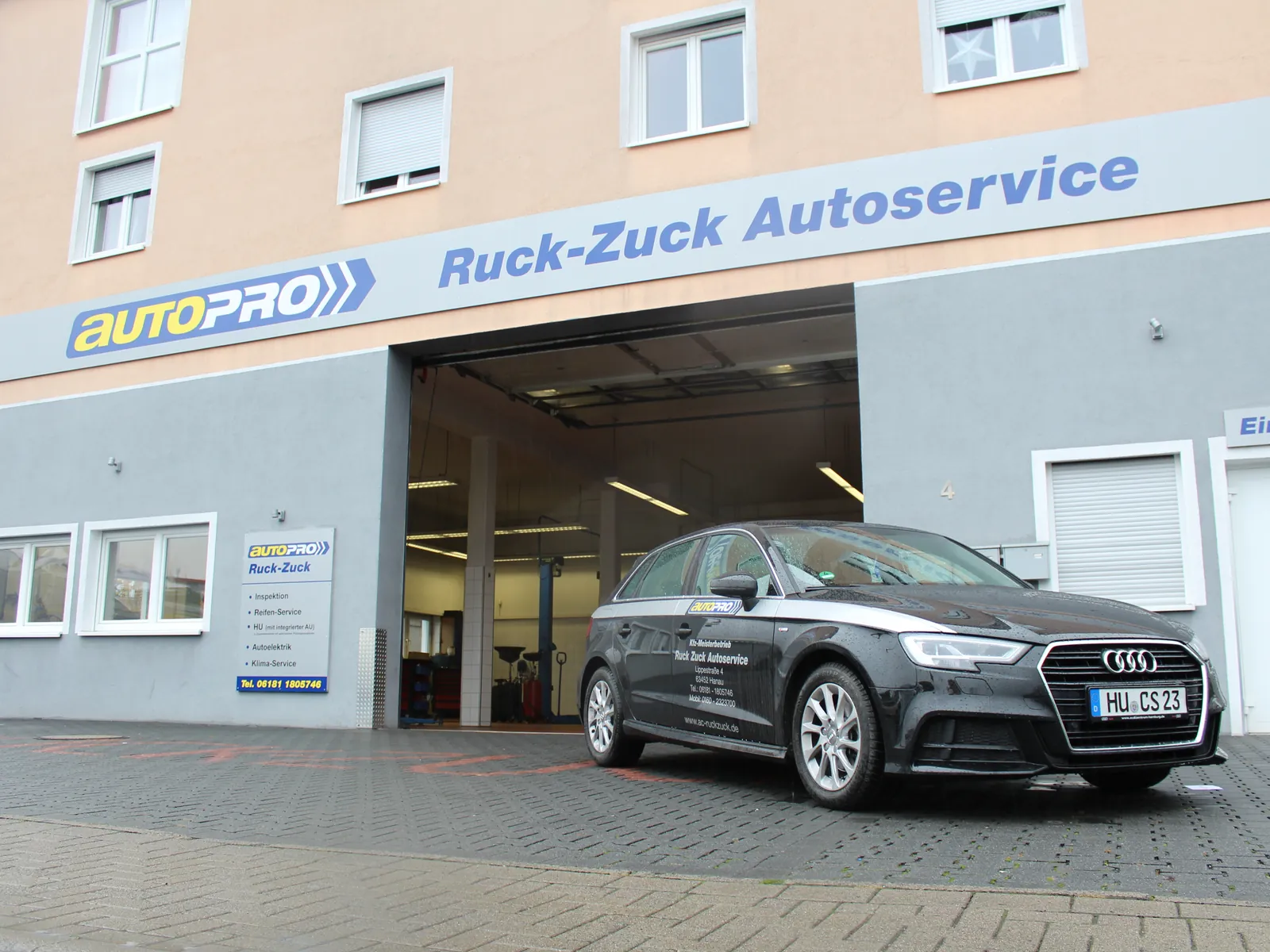 Fahrzeug vor der geöffneten Werkstatthalle