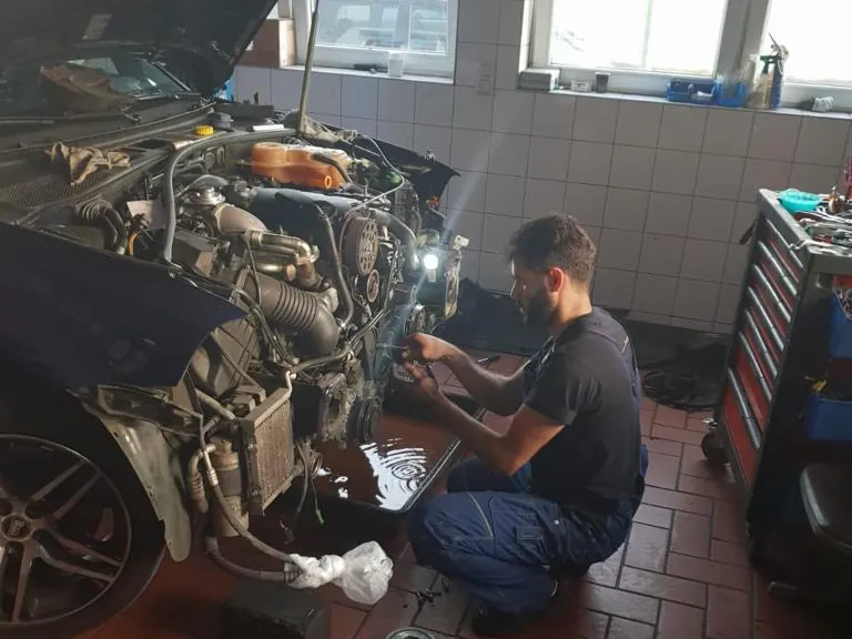 Arbeiten am geöffneten Motorraum in der Halle